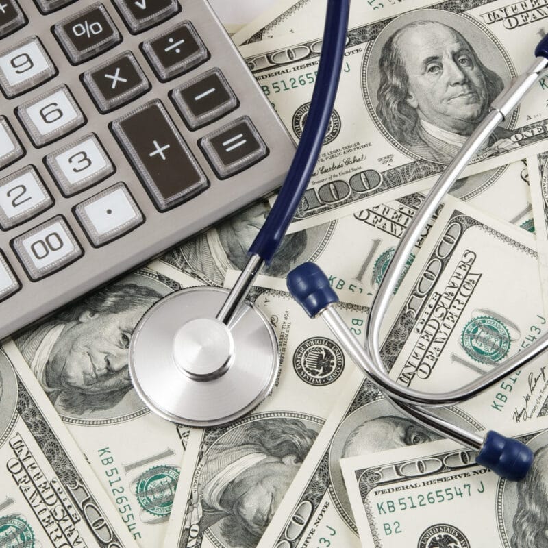 calculator and stethoscope on pile of money showing ideal price transparency